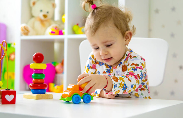 L'enfant joue avec les jouets dans la chambre. Concentration sélective. Bébé. - Photo, image