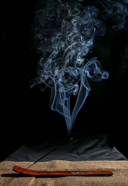 Indische Räucherstäbchen mit Rauch auf schwarzem Hintergrund in Nahaufnahme - Foto, Bild