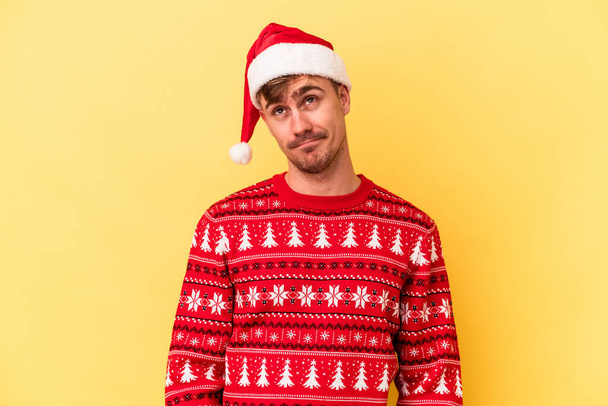 Genç beyaz adam, sarı arka planda izole edilmiş bir şekilde Noel 'i kutluyor. Amaçlarına ve amaçlarına ulaşma hayali kuruyor. - Fotoğraf, Görsel