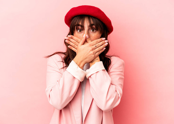 Young Argentinian woman isolated on pink background shocked covering mouth with hands. - Foto, afbeelding