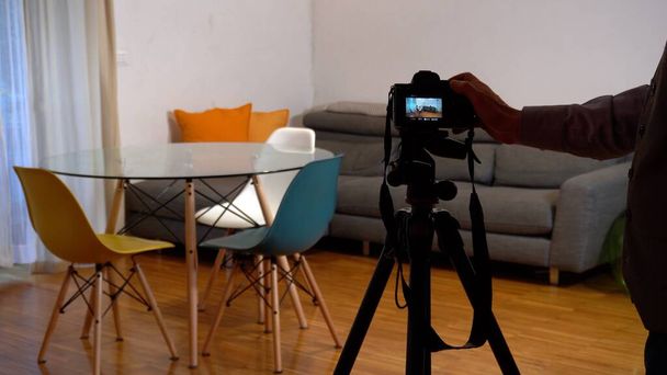 photo of professional photographer filming new flat on digital devices and video camera on the tripod. focus in background - Photo, Image