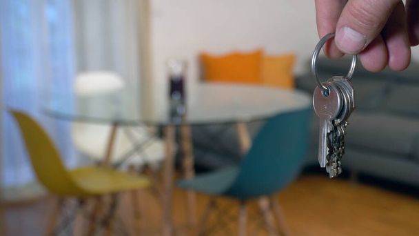 mano sosteniendo una llave con un fondo borroso de la sala de luz - Foto, Imagen