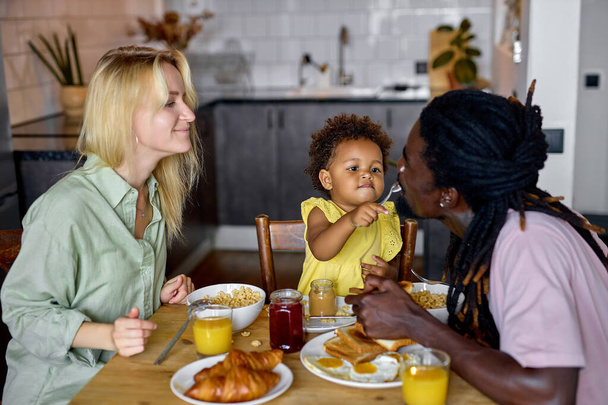 family spoon feeding each other, sitting behind table during breakfast or lunch - Φωτογραφία, εικόνα