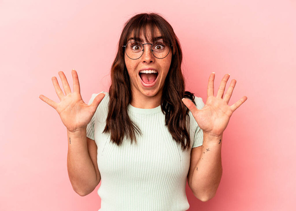 Young Argentinian woman isolated on pink background receiving a pleasant surprise, excited and raising hands. - Foto, immagini