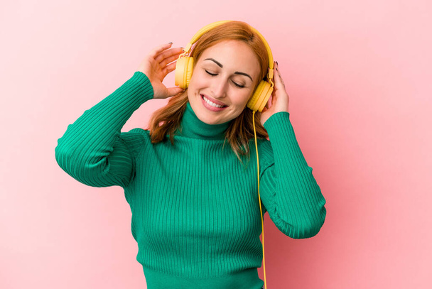 fiatal kaukázusi nő hallgat zenét elszigetelt rózsaszín háttér - Fotó, kép