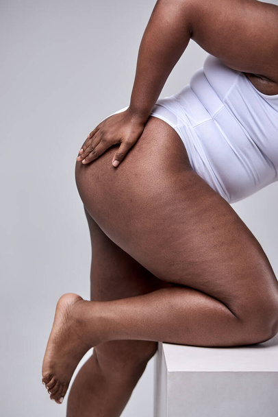 Plus Size Model. Woman Hips Close Up. Cropped Female In White Bodysuit, Posing On Gray Studio - Foto, imagen