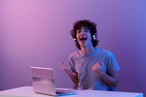 gamer in headphones in front of laptop entertainment violet background - Valokuva, kuva