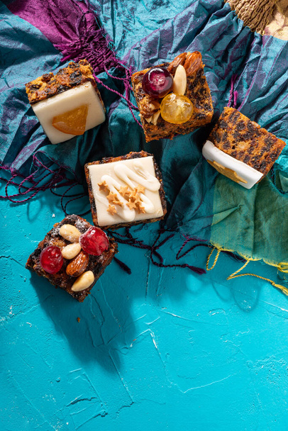 Dulces y ricos pudines de Navidad cargados de frutos secos, frutos secos y especias sobre un vibrante fondo de turquesa oriental - Foto, imagen