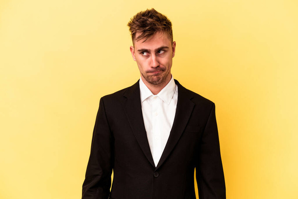 Young caucasian business man isolated on yellow background confused, feels doubtful and unsure. - Zdjęcie, obraz