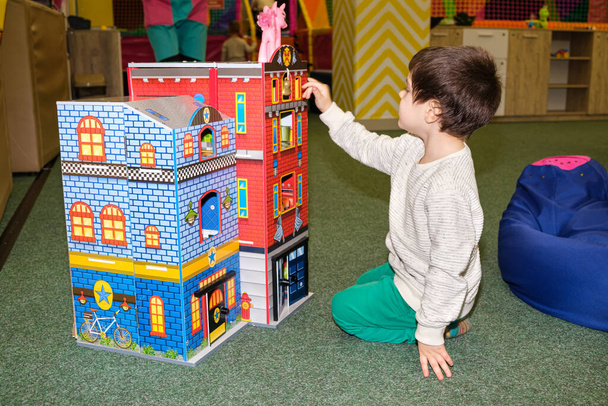 A 4-year-old boy plays in the playroom in the childrens entertainment center with a toy big castle. - Photo, Image