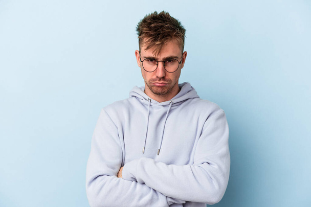 Young caucasian man isolated on blue background tired of a repetitive task. - Foto, immagini