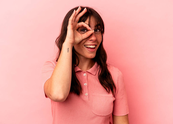 Young Argentinian woman isolated on pink background excited keeping ok gesture on eye. - Photo, Image