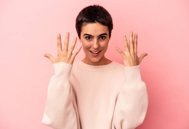 Young caucasian woman isolated on blue background showing number ten with hands. - Foto, Imagen