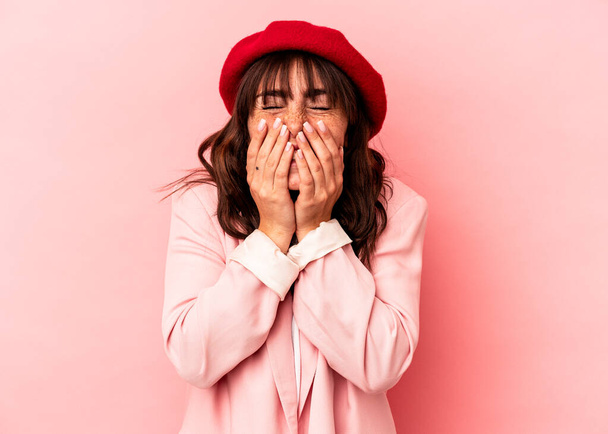 Jeune femme argentine isolée sur fond rose riant de quelque chose, couvrant la bouche avec les mains. - Photo, image