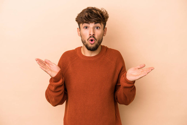 Young arab man isolated on beige background surprised and shocked. - Φωτογραφία, εικόνα
