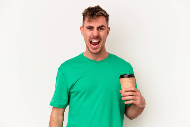Fiatal kaukázusi férfi kezében egy elvitelre kávé elszigetelt fehér háttér sikoltozó nagyon dühös és agresszív. - Fotó, kép
