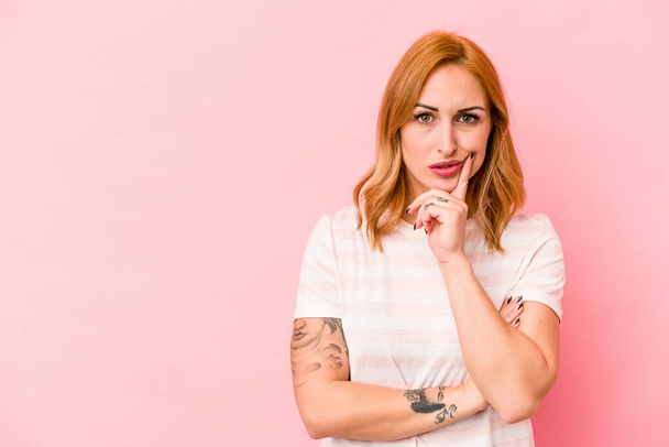Young caucasian woman isolated on pink background looking sideways with doubtful and skeptical expression. - Photo, Image