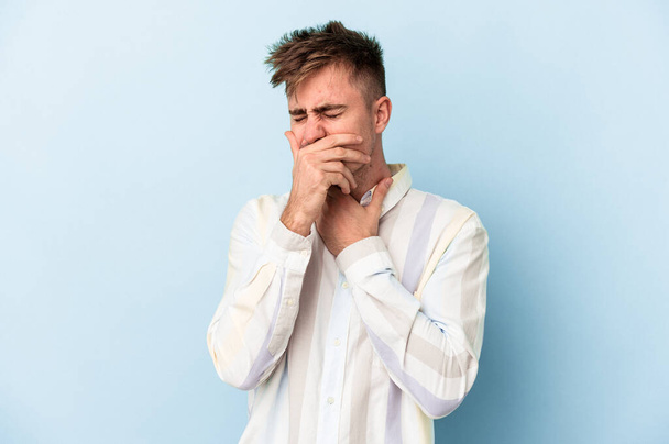 Young caucasian man isolated on blue background suffers pain in throat due a virus or infection. - Photo, Image