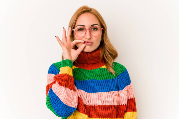 Young caucasian woman wearing a sweater with stripes isolated on white background with fingers on lips keeping a secret. - Foto, Bild