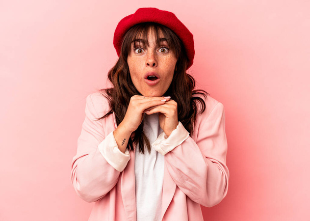 Young Argentinian woman isolated on pink background praying for luck, amazed and opening mouth looking to front. - Foto, Imagen