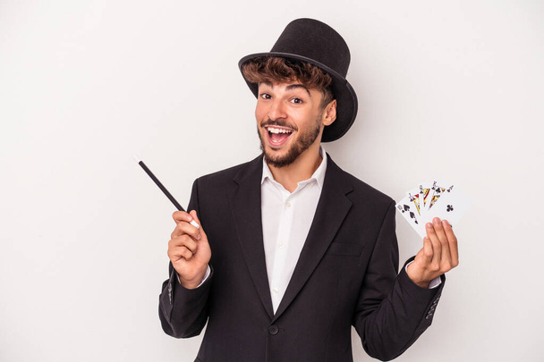 Young arab wizard man holding a magic cards and wand isolated on white background - Foto, Bild