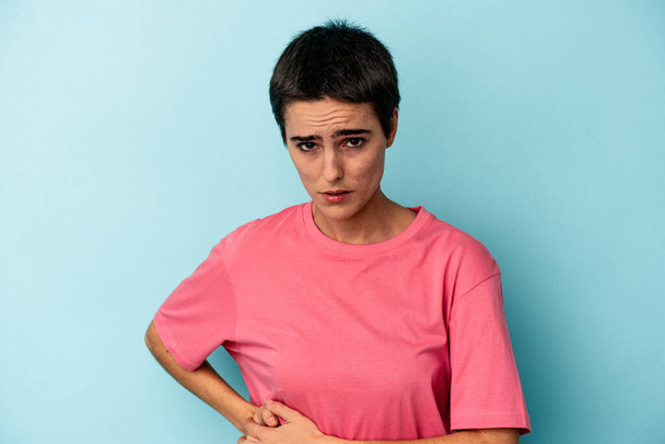 Young caucasian woman isolated on blue background having a liver pain, stomach ache. - 写真・画像