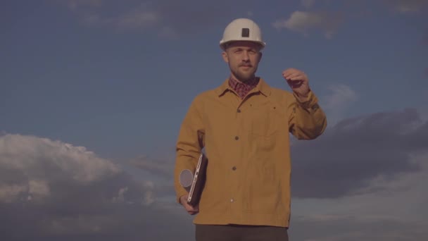 Contratista de construcción en obra corrigiendo el casco duro - Imágenes, Vídeo