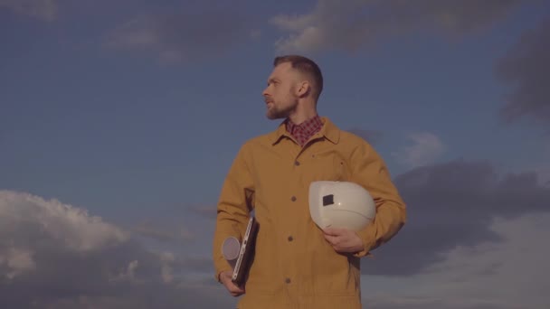 Construction industry worker holds helmet, plans and laptop - Materiał filmowy, wideo