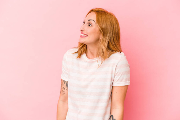 Young caucasian woman isolated on pink background laughs and closes eyes, feels relaxed and happy. - Photo, Image