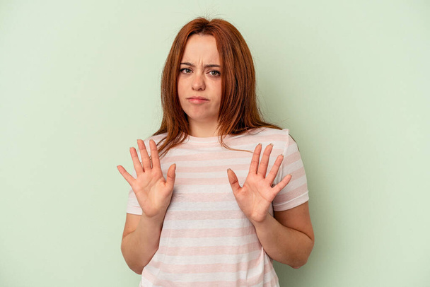 Young caucasian woman isolated on green background rejecting someone showing a gesture of disgust. - Photo, Image