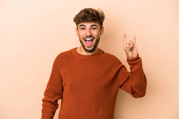 Young arab man isolated on beige background showing a horns gesture as a revolution concept. - Φωτογραφία, εικόνα