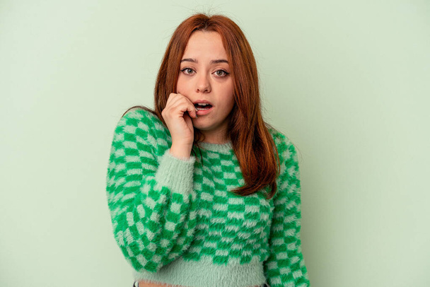 Young caucasian woman isolated on green background biting fingernails, nervous and very anxious. - Photo, Image