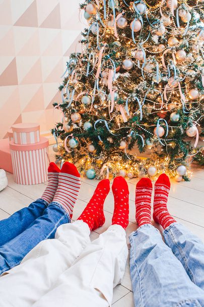 Foto de cerca de los pies de la familia en calcetines de lana junto al árbol de Navidad - Foto, Imagen