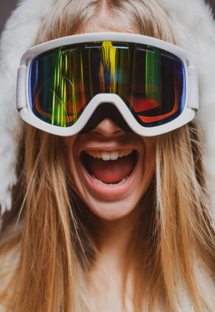 Excited amazed woman in ski goggles. Close up winter portrait of young amazing girl with snow goggles. Funny face. - Foto, Imagem