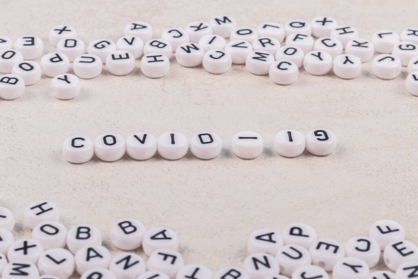 les mots covid 19 sont disposés en lettres sur un fond rose ou blanc. il y a beaucoup d'inscriptions de jouets à proximité - Photo, image