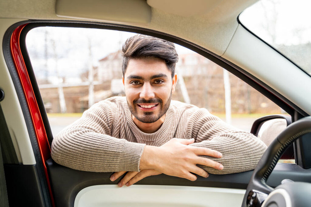 Man casually dressed with hands holding driving wheel riding car at daytime - Foto, imagen