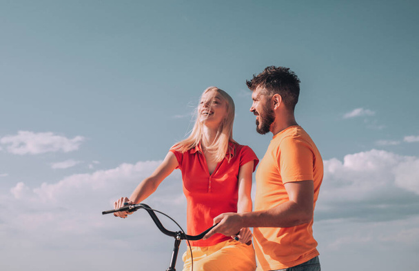 Summer woman with retro bike on blue sky background. Happy loving couple. Greatest Love Stories. Couple in summer dress rides a bike. Couple with vintage bike. - Photo, image