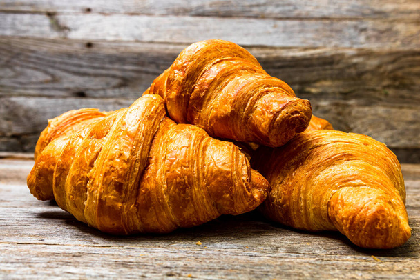 Leckere, frische Croissants isoliert auf Holzbrettern. Französisches Frühstückskonzept. - Foto, Bild