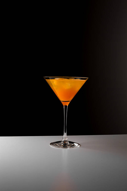 Fruit healthy cocktail from mango juice, orange peel spiral and ice on dark black background. - Foto, Bild