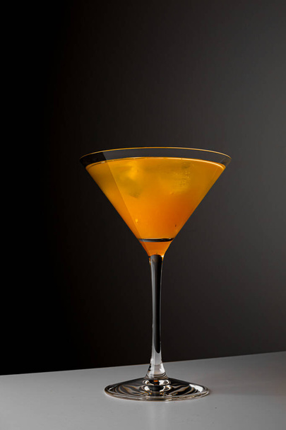 Fruit healthy cocktail from mango juice, orange peel spiral and ice on dark black background. - Valokuva, kuva