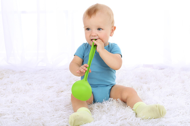 Cute baby boy with kitchen spoon on carpet in room - Foto, Bild