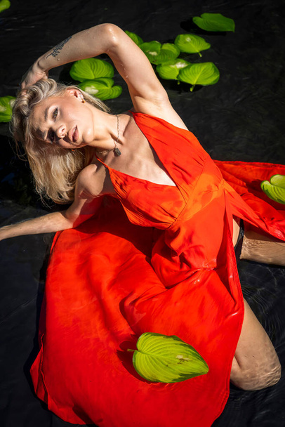 Una hermosa modelo rubia posa en lencería al aire libre en una piscina de agua - Foto, Imagen