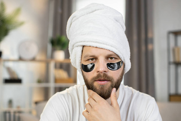 Caucasian man with white towel on his head and black patches under eyes - Foto, immagini