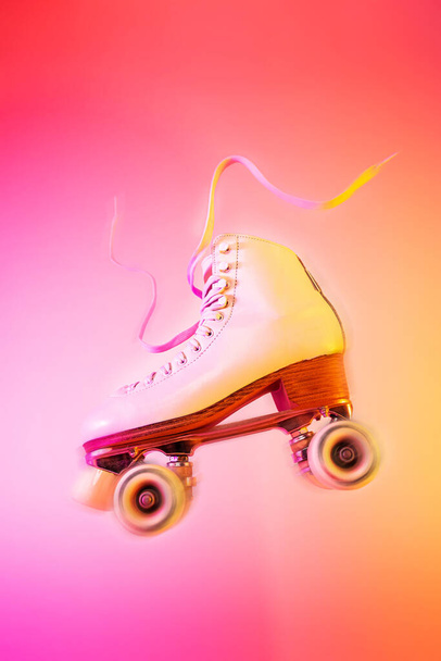 Classic white leather roller skate levitating on the vivid pink and orange background. Sports equipment and recreation. Dynamic pop art poster layout with free copy (text) space. - Foto, immagini