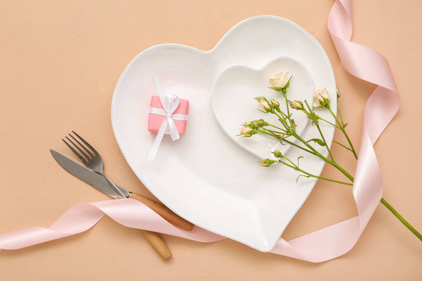 Mooie tafel, bloemen en cadeau voor Valentijnsdag op beige achtergrond - Foto, afbeelding