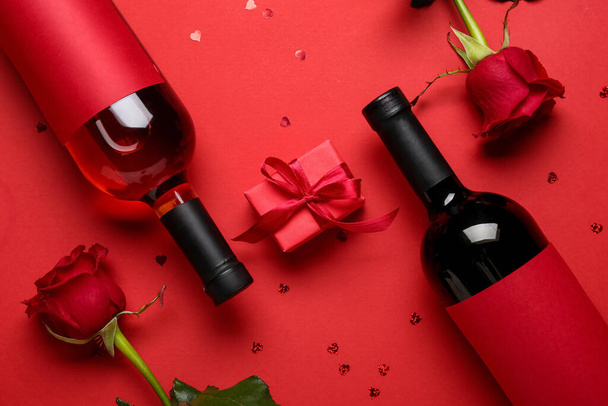 Flaschen Wein, Rosen und Geschenk zum Valentinstag auf rotem Hintergrund - Foto, Bild