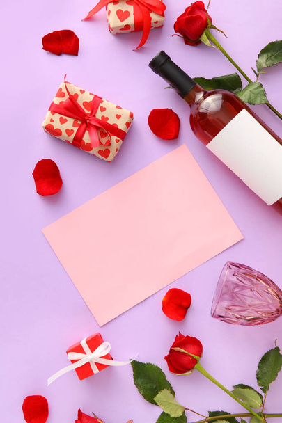 Composición con tarjeta en blanco, botella de vino, copa y regalos para el Día de San Valentín sobre fondo lila - Foto, imagen