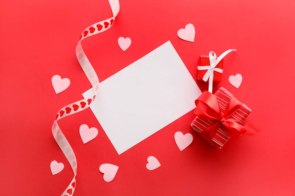 Összetétel üres kártyával, papírszívvel és ajándékokkal Valentin-napra vörös alapon - Fotó, kép