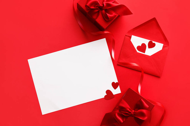 Composición con tarjeta en blanco, sobre y regalos para el Día de San Valentín sobre fondo rojo - Foto, Imagen