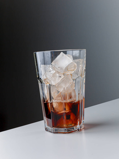 Cola with Ice Cubes. Glass of cola. Copy Space. Pour soft drink in glass with ice splash on dark background. glass of cola with ice isolated. Soft drink glass with ice splash on cool smoke background. - Φωτογραφία, εικόνα